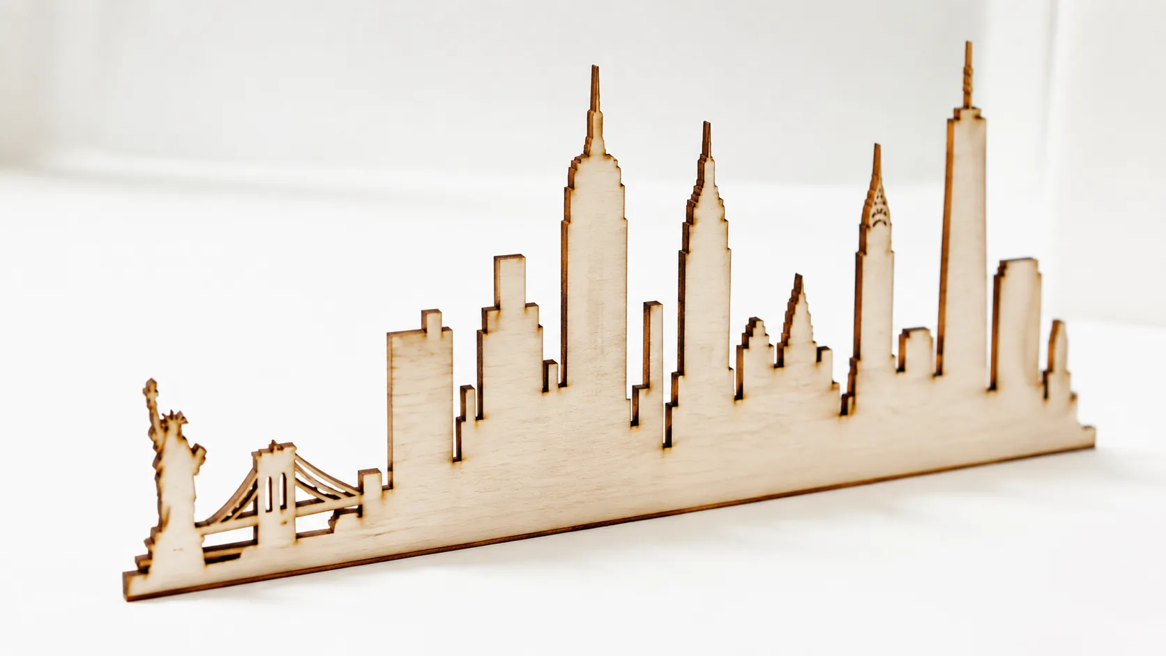 Finished laser-cut city skyline art made from 3mm basswood, displayed on workshop table