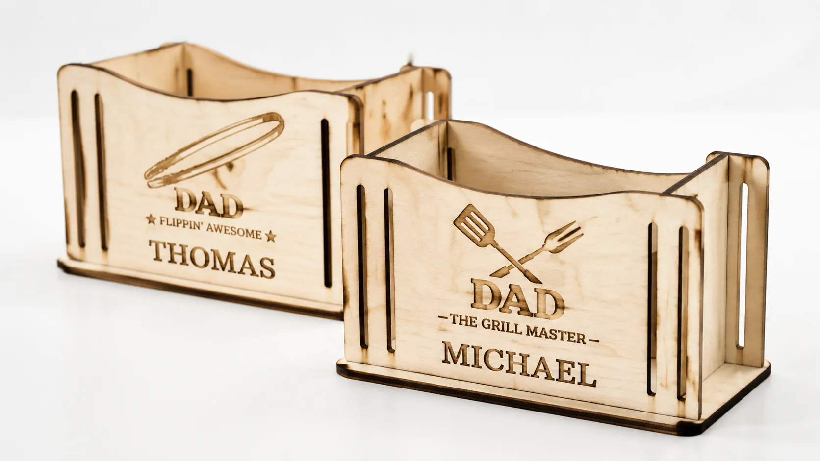 Laser-cut BBQ tool holders made from 3mm basswood, displayed on workshop table with engraved names and personalization