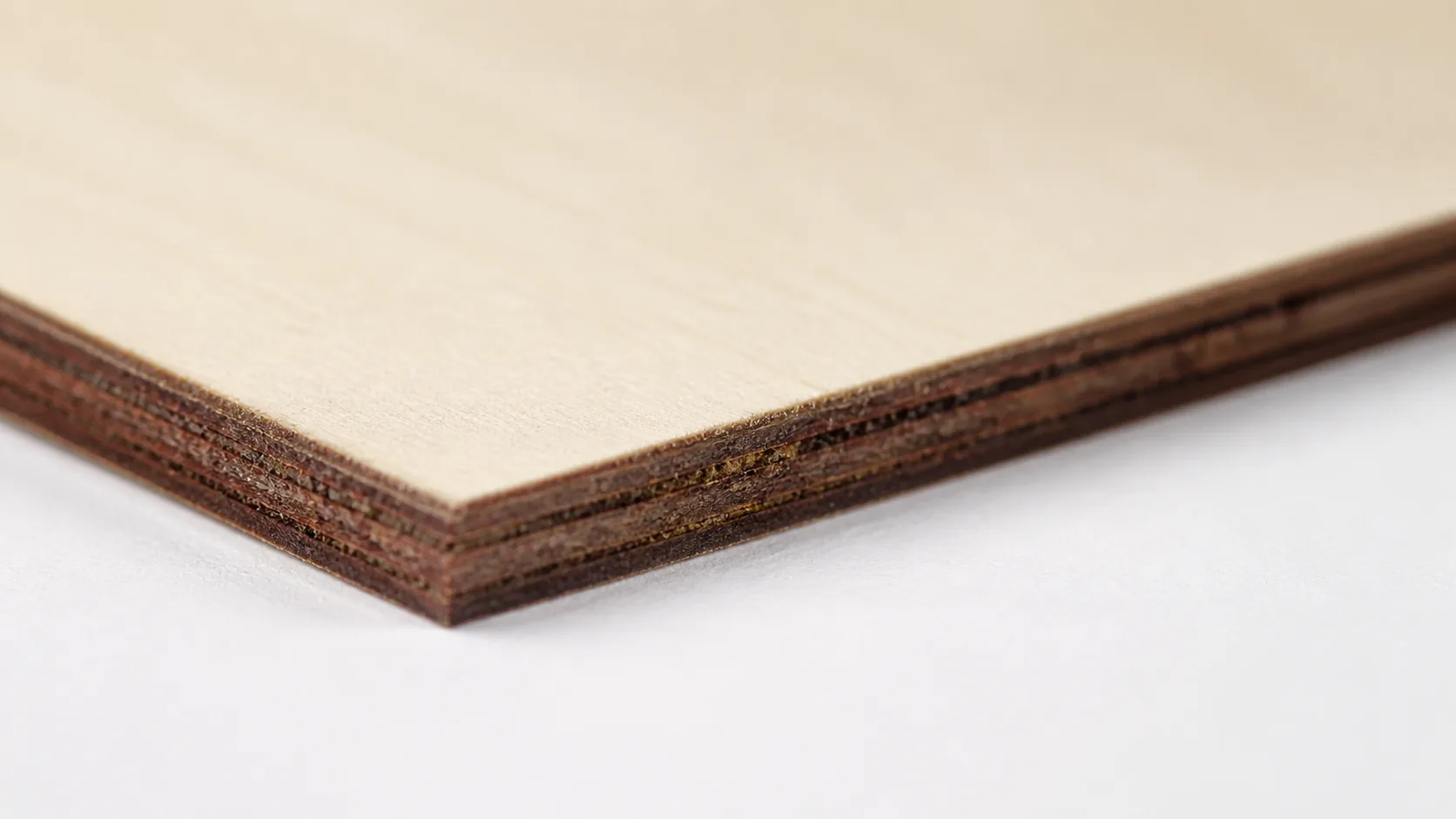 Close-up of 3mm basswood sheet edge showing pale cream surface and laser-cut detail