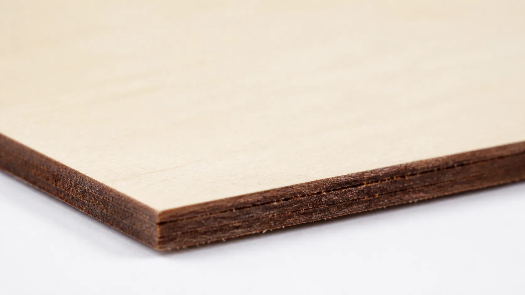 Close-up of 3mm basswood sheet edge showing pale cream surface and laser-cut detail